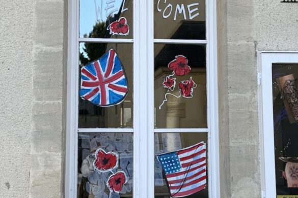 shop window in Bayeux with American, British, and Canadian flags and a welcome sign during D-Day anniversary week