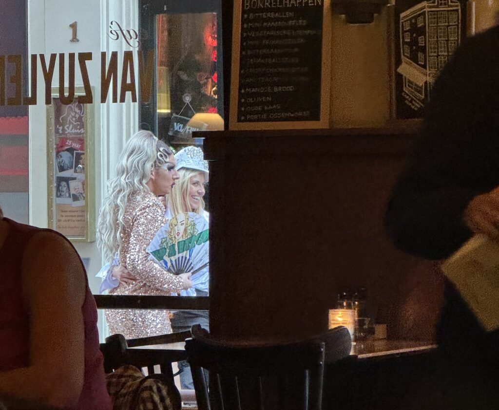 costumed people outside a window in amsterdam while diners sit inside a cafe
