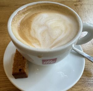 cappuccino in a white cup on a wooden table at a cafe in amsterdam