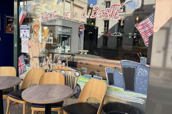 shop window in Bayeux showing paratroopers, Allied flags, and “Place de la Liberté” decoration during D-Day anniversary week