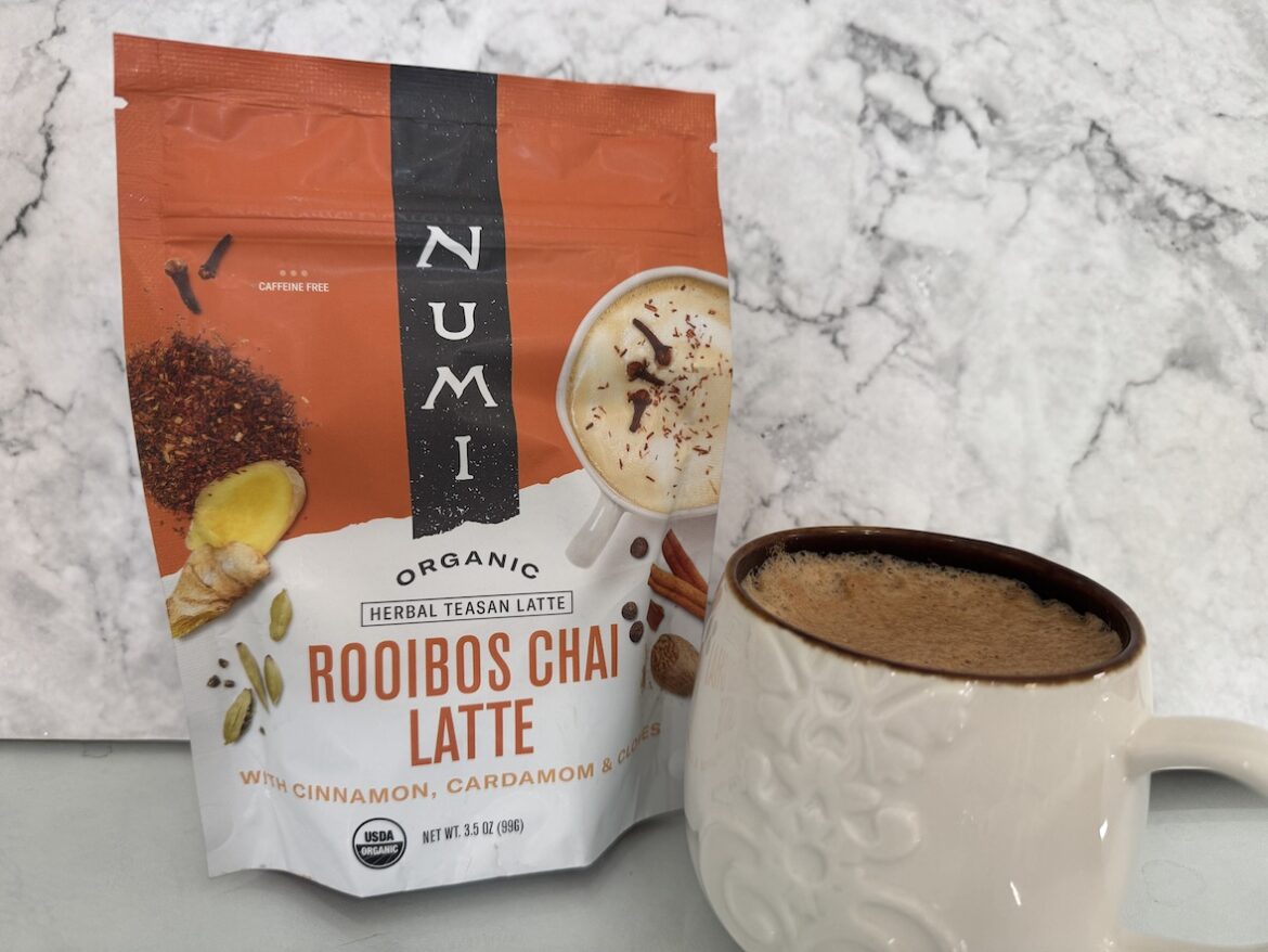 numi rooibos chai latte mix prepared in a mug with creamy foam and packaging beside it