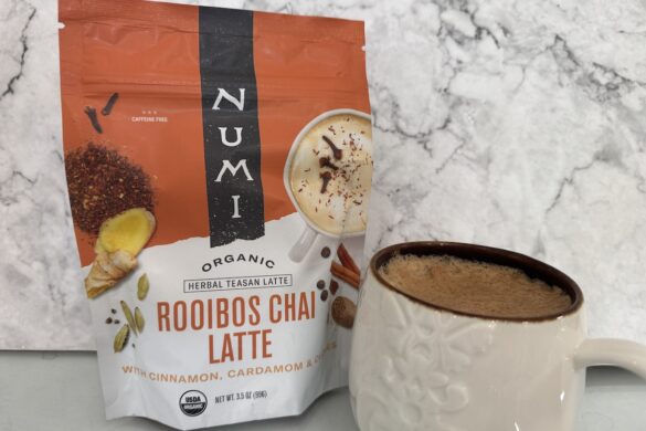 numi rooibos chai latte mix prepared in a mug with creamy foam and packaging beside it