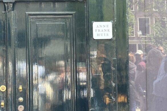 dark green door of the Anne Frank House in Amsterdam with reflection of people and photographer in the glass