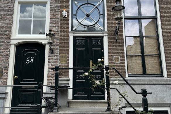 narrow amsterdam canal house with black and white facade, tall windows, and a bicycle parked in front