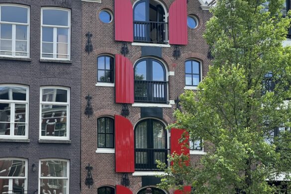 Amsterdam canal house with red shutters and a stepped gabled facade