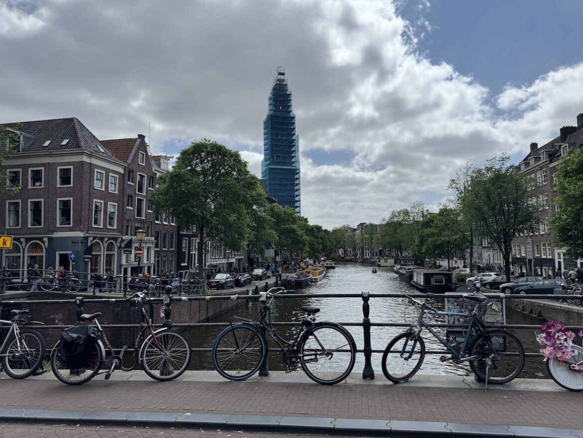 amsterdam canal with bicycles along the bridge and the westerkerk tower rising in the background