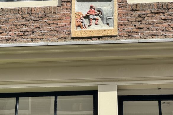 decorative gevelsteen relief with a small figurative scene embedded in a brick building facade in amsterdam