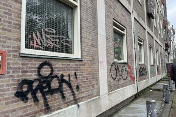 Graffiti tags on a brick building along a side street in Amsterdam