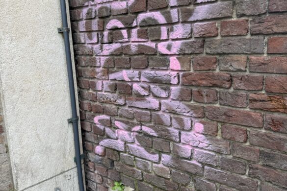 Pink monkey-like street art painted on a brick wall in Amsterdam