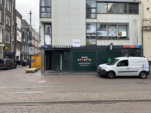 Street scene in Amsterdam with McDonald’s, a Starbucks under renovation, and Smoking Phone & More shop