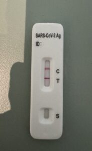rapid COVID-19 antigen test showing positive result with two lines on test strip on a tabletop