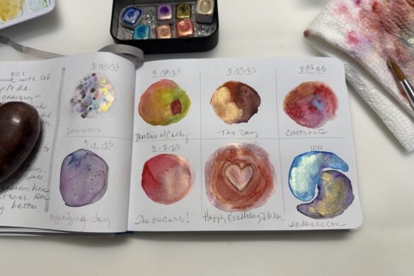 sketchbook page with metallic watercolor swatches showing shimmering pigments in different colors with paint sets nearby