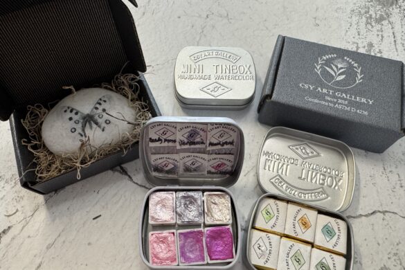 metallic watercolor paint tins in small travel cases with shimmering colors displayed