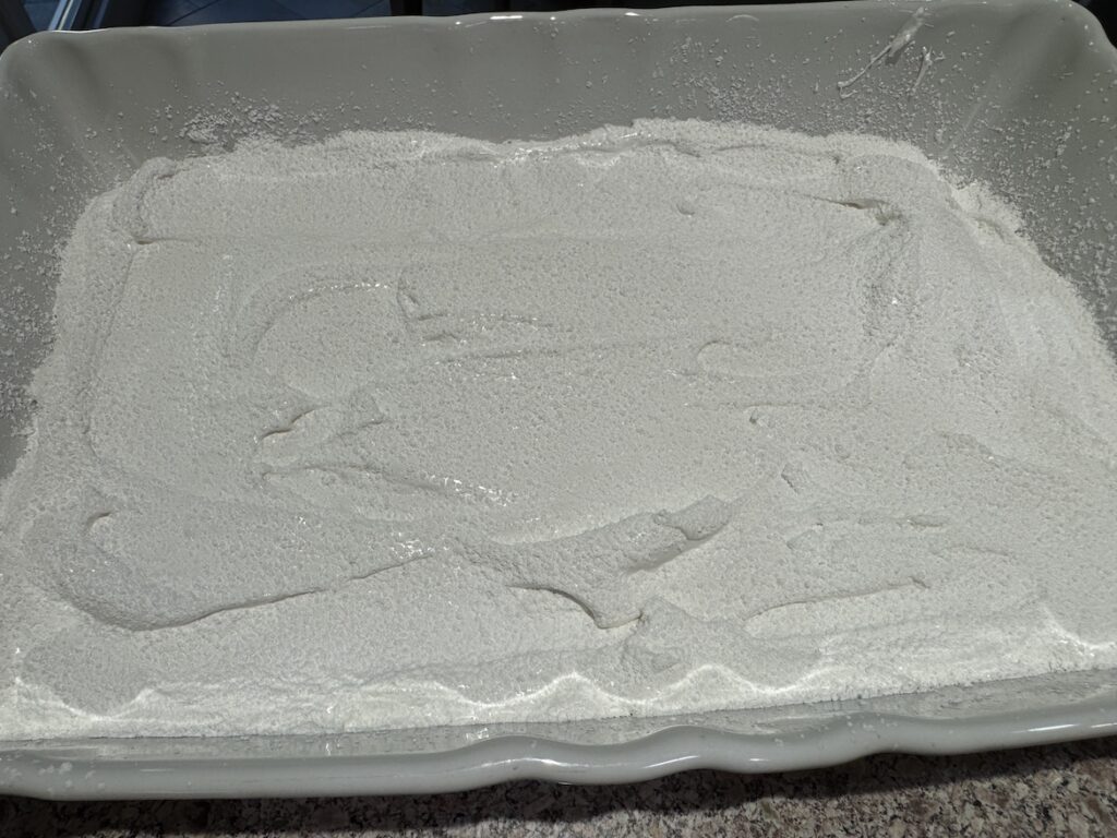 Whipped homemade marshmallow mixture spread into a rectangular pan before setting