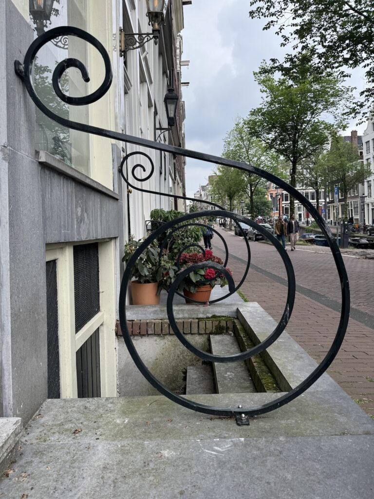 Decorative wrought-iron stair railing outside a canal house in Amsterdam