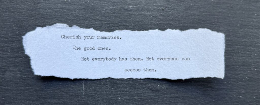 Torn typewritten note beginning “Cherish your memories” on black stone