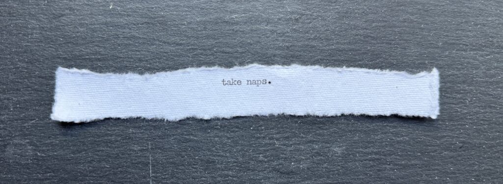 Torn typewritten note reading “Take naps.” on black stone